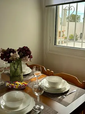 a table with plates and glasses and a vase of flowers at Easy Stay Airport Athens in Koropíon