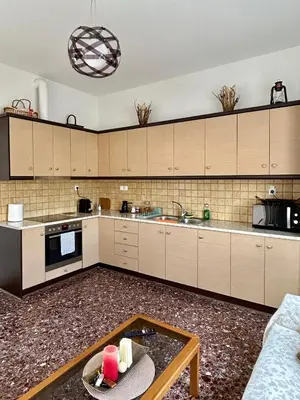 a kitchen with white cabinets and a table in it at Easy Stay Airport Athens in Koropíon