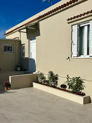 a white house with plants in front of it at Easy Stay Airport Athens in Koropíon