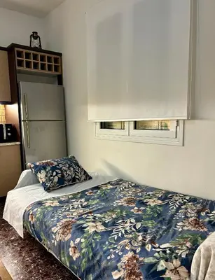 a bedroom with a bed with a floral comforter and two windows at Easy Stay Airport Athens in Koropíon