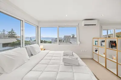 a white bedroom with a large bed and large windows at Apt 1' From The Sea With Private Terrace & BBQ in Vari