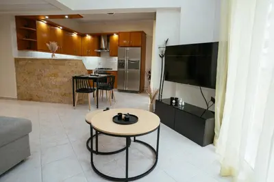 a living room with a tv and a table and a kitchen at Comfy stay 2BR flat 1Gbps 4 min walk from metro in Athens