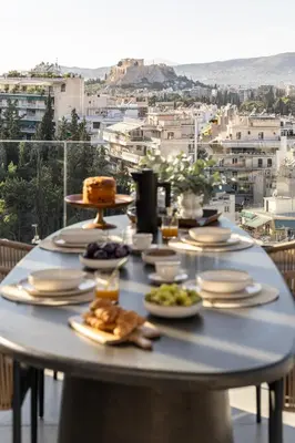 a table with plates of food on a balcony at Urban Forty One Acropolis-view penthouse in Athens