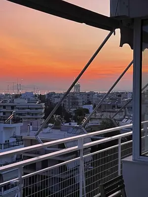a view of a city at sunset from a balcony at Glyfada Residence Top Floor With Sea & Tower View in Athens