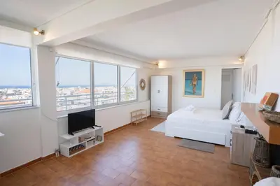 a large white room with a bed and a tv at Glyfada Residence Top Floor With Sea & Tower View in Athens