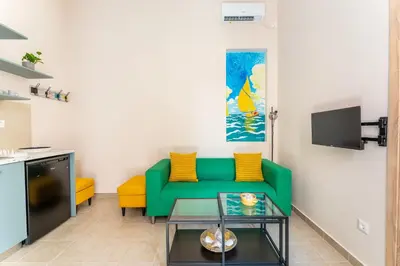 a living room with a green couch and a tv at A2 Porto Living in Piraeus