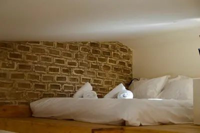 a bed with white pillows and a brick wall at Mosaics Agora Boutique Hotel in Athens
