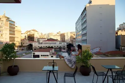 a woman standing on a balcony with a view of a city at Mosaics Agora Boutique Hotel in Athens