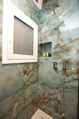 a bathroom with a marble wall with a mirror at Luxury apartments near athens city center in Athens