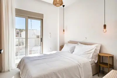 a white bedroom with a bed and a large window at Artemis House Athens in Athens