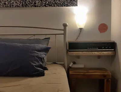 a bedroom with a bed with a light on the wall at Back to the 50's near metro by Traser in Athens