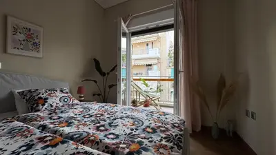 a bedroom with a bed with a floral comforter and a window at Cozy apartment 10 min to acropolis in Athens
