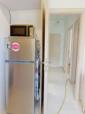 a refrigerator with a microwave on top of it in a room at Glifada Luxury Two-Bedroom Suite in Athens