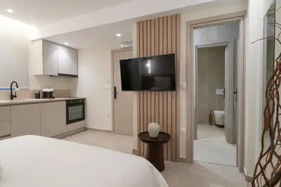 a bedroom with a bed and a kitchen with a television at ASPENGR Monastiraki Hotel & Apartments in Athens