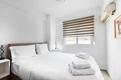 a white bedroom with a white bed and a window at Elysian Lycabettus - Horizon in Athens