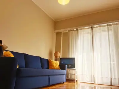 a blue couch in a living room with a window at Charming Plaka Retreat in Athens in Athens