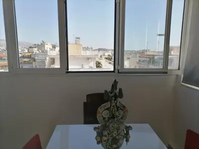 a table with a vase on it in a room with windows at Sunny Penthouse in the Center of Athens in Athens