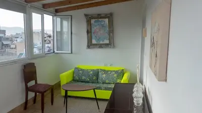 a living room with a green couch and a table at Sunny Penthouse in the Center of Athens in Athens