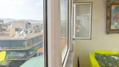 a living room with a window and a yellow couch at Sunny Penthouse in the Center of Athens in Athens