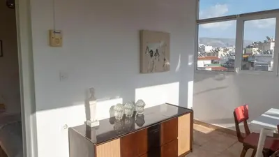 a living room with a table and a window at Sunny Penthouse in the Center of Athens in Athens