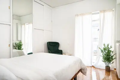 a white bedroom with a large bed and a green chair at Houseloft The Viewpoint Athens in Athens