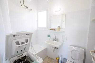 a white bathroom with a washing machine and a sink at Beachfront Lagonisi Apt 1 Minute From Grand Resort in Kalívia Thorikoú