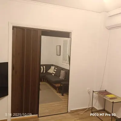 a door leading into a living room with a couch at Quiet room, hall, shared bathroom and kitchen in Athens