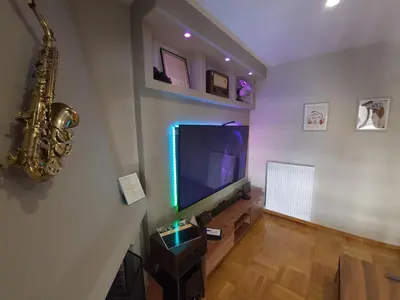 a living room with a flat screen tv and a saxophone at POSEIDON Executive Suite in Athens