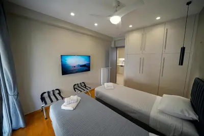 a bedroom with two beds and a tv on the wall at POSEIDON Executive Suite in Athens