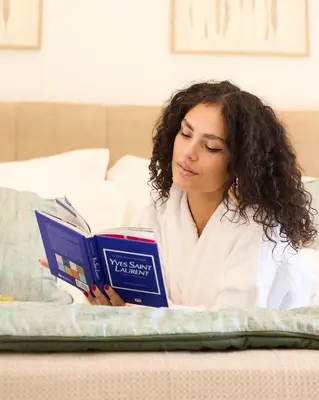 a woman laying in bed reading a book at Acropolis view modern studio in Athens