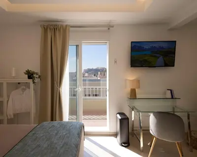 a bedroom with a bed and a desk and a window at Acropolis view modern studio in Athens