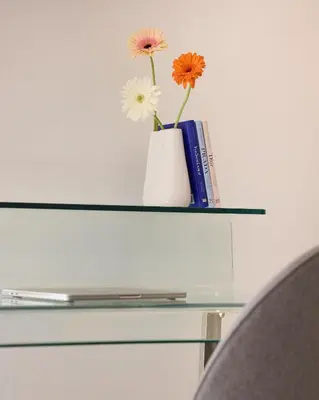 a vase with flowers and a book on a glass shelf at Acropolis view modern studio in Athens