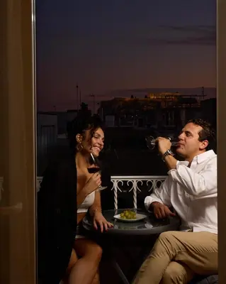 a group of people sitting on a balcony drinking wine at Acropolis view modern studio in Athens