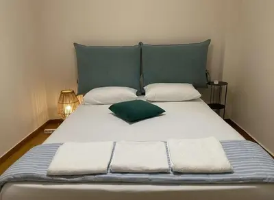 a large white bed with a green pillow on it at Lydia Apartment Comfortable 2BR near Hospital in Athens
