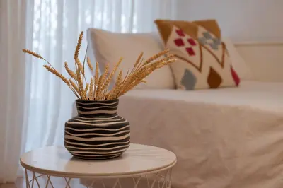 a black and white vase on a table next to a bed at Spacious & central 2BR apt in Agia Paraskevi in Athens