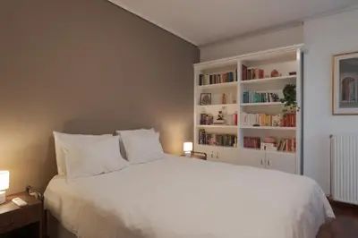 a bedroom with a white bed with book shelves at Spacious & central 2BR apt in Agia Paraskevi in Athens