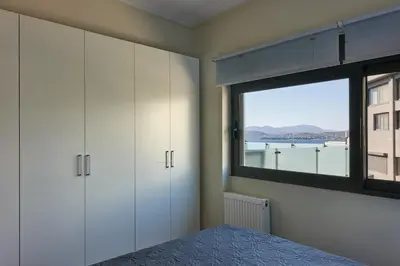 a bedroom with white cabinets and a large window at Deep Blue Luxury Escape Heated Pool & Sea View in Saronida