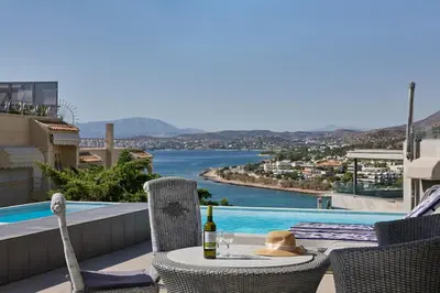 a table with a bottle of wine sitting on a balcony at Deep Blue Luxury Escape Heated Pool & Sea View in Saronida