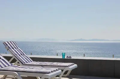 two chairs sitting on a balcony overlooking the water at Deep Blue Luxury Escape Heated Pool & Sea View in Saronida