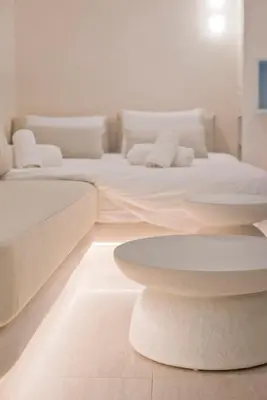 a living room with two beds and a table at Radiant Voula Studio, a stone's throw from the Sea in Athens
