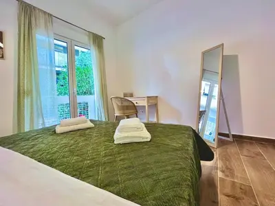 a bedroom with a bed with a green blanket and a mirror at Earthy Retreat in Central Athens Fully renovated in Athens