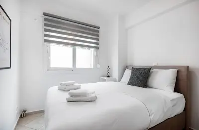 a white bedroom with a large bed with towels on it at Elysian Lycabettus - Panorama in Athens