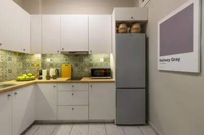 a kitchen with white cabinets and a refrigerator at Eclectic Studio near Kallimarmaro in Athens