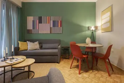 a living room with a couch and a table and chairs at Eclectic Studio near Kallimarmaro in Athens