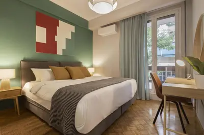 a bedroom with a large bed and a desk and a window at Eclectic Studio near Kallimarmaro in Athens