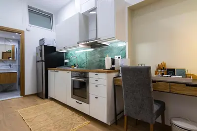 a kitchen with white cabinets and a black refrigerator at Timeless 1 bedroom Luxury at Panathenaic Stadium in Athens