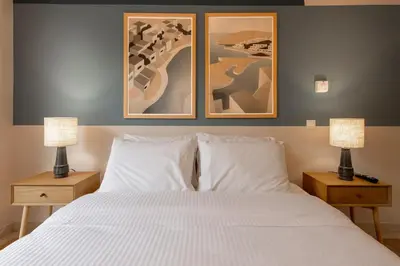 a bedroom with a bed with two lamps and two pictures at Zen Vouliagmeni Beach Apartment 2 in Athens