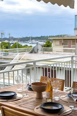 a wooden table with wine glasses on a balcony at Zen Vouliagmeni Beach Apartment 2 in Athens
