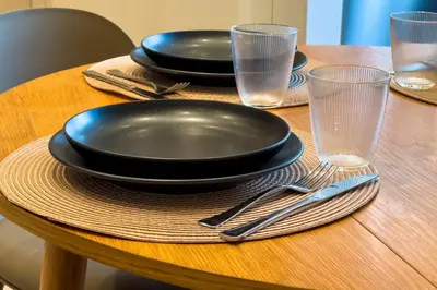 a wooden table with black plates and glasses on it at Zen Vouliagmeni Beach Apartment 2 in Athens