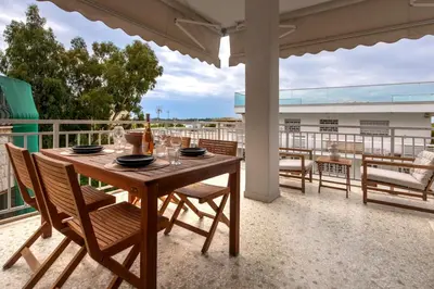 a wooden table with wine glasses on a balcony at Zen Vouliagmeni Beach Apartment 2 in Athens